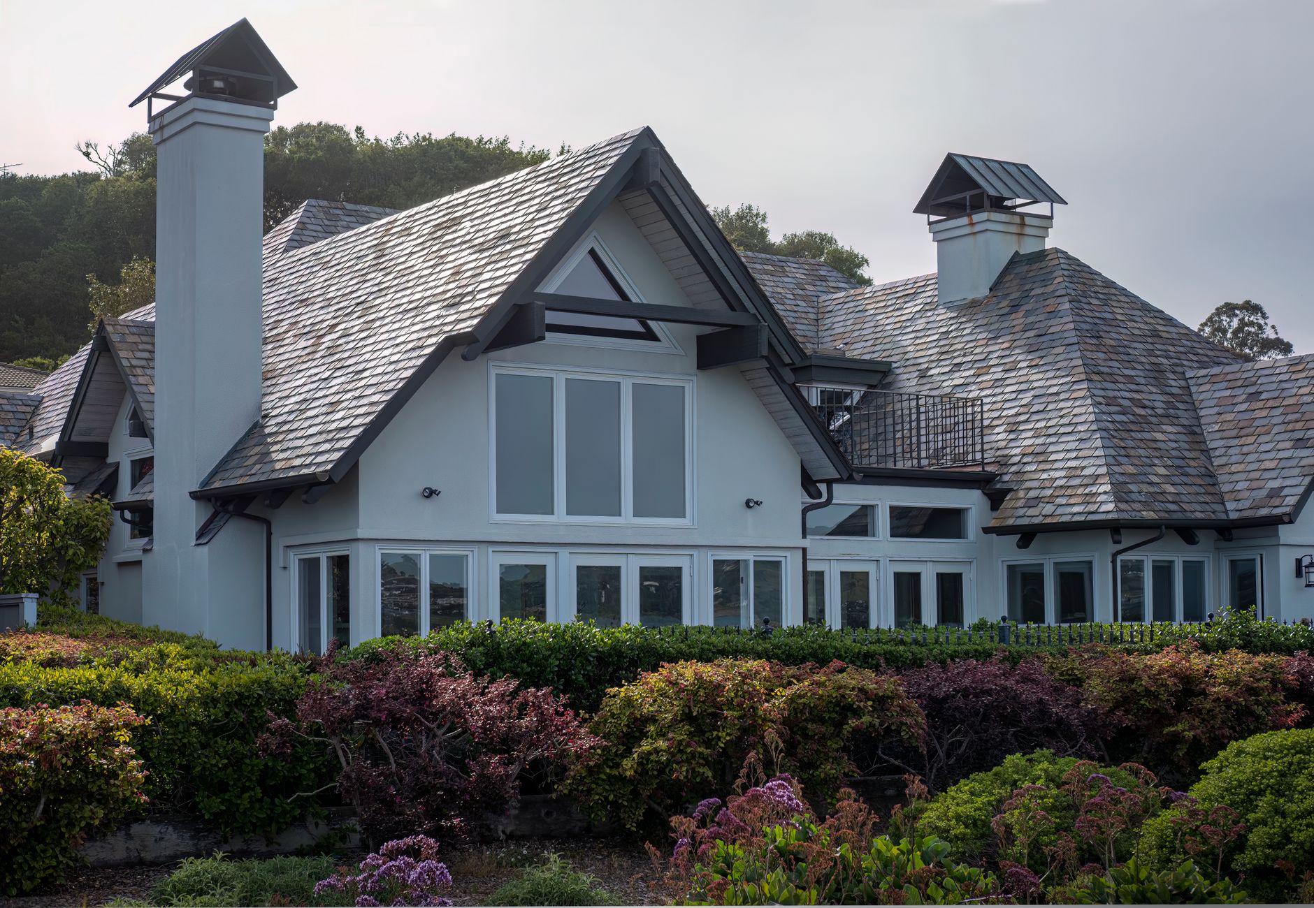 Residential home with a slate shingle roof, dormers and two chimneys