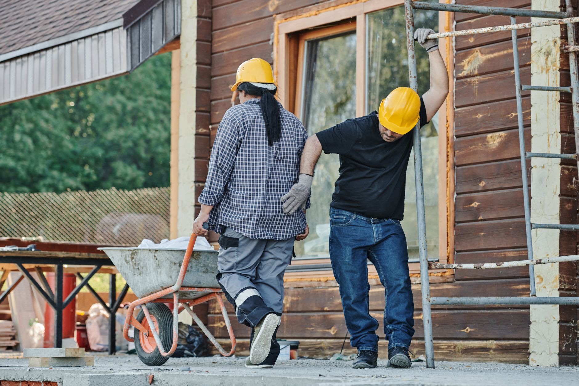 Two construction workers in hard hats working on a house exterior